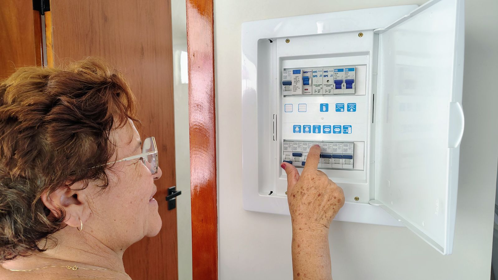 A hand resetting a switch inside a domestic consumer unit