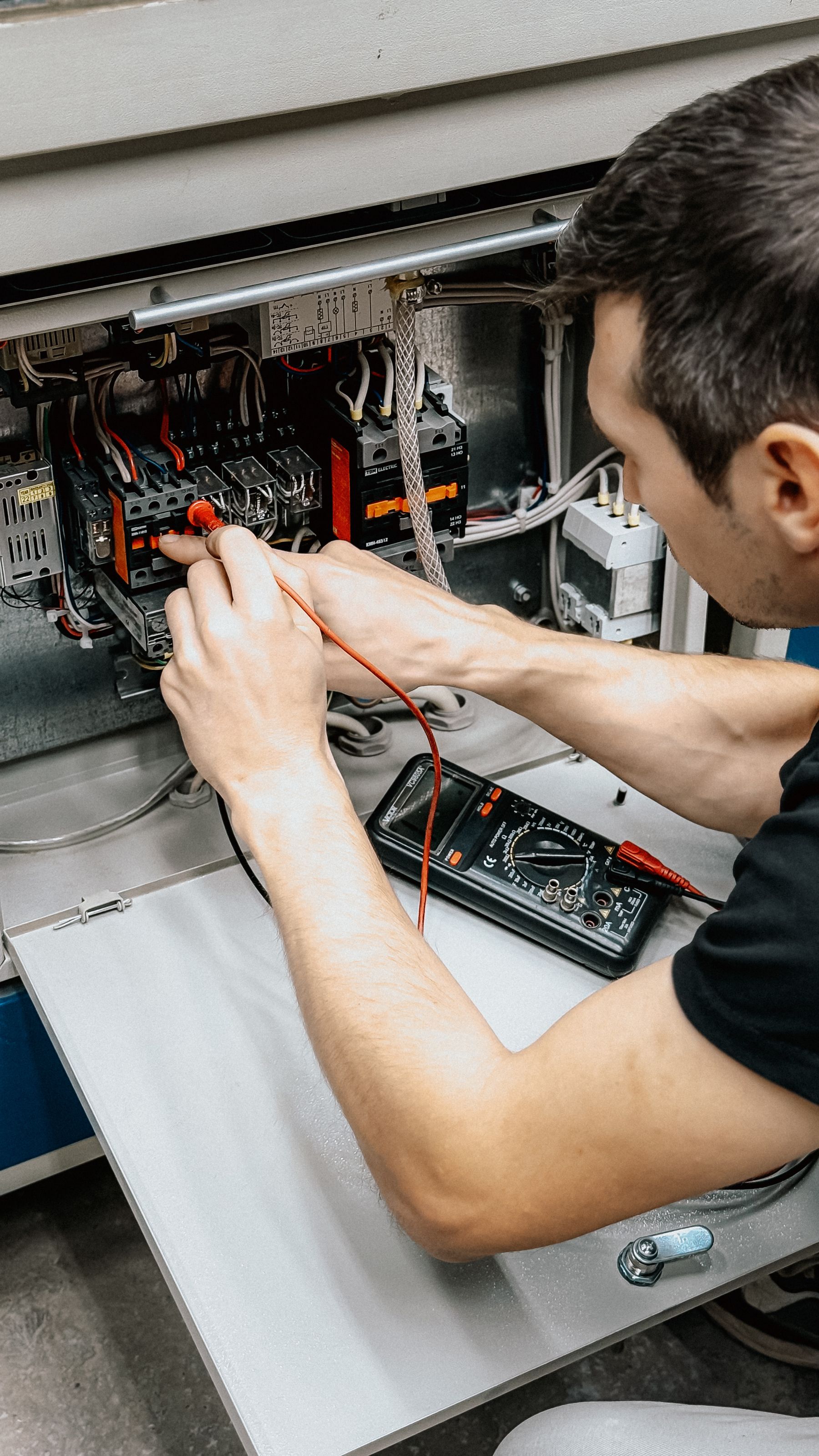 An engineer testing connections inside an electrical panel with a multimeter