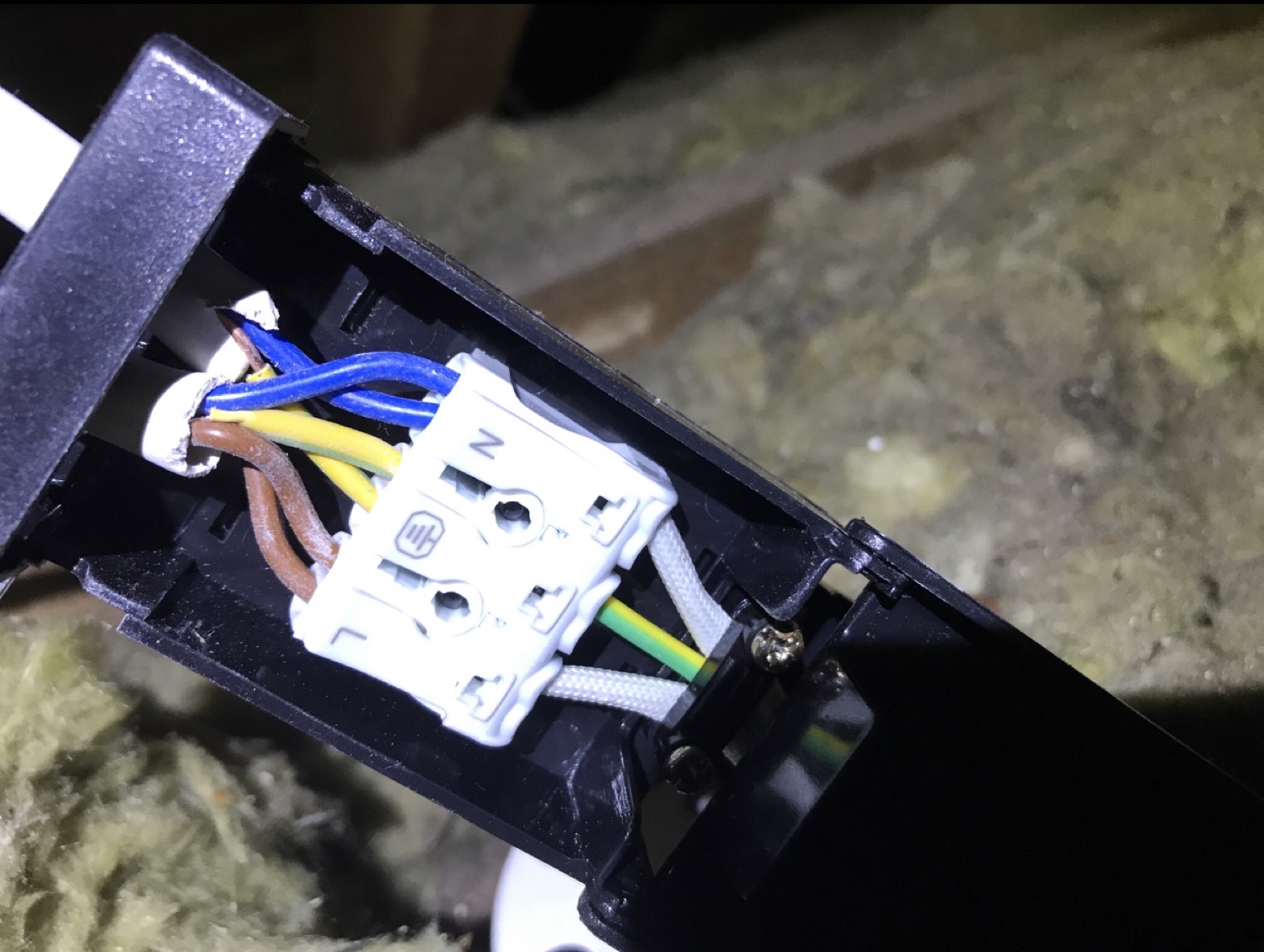 A light fitting terminated in the loft above insulation — connections made off properly rather than twisted and taped.